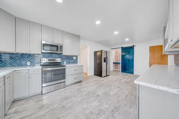 a kitchen with granite countertop a refrigerator and a stove top oven