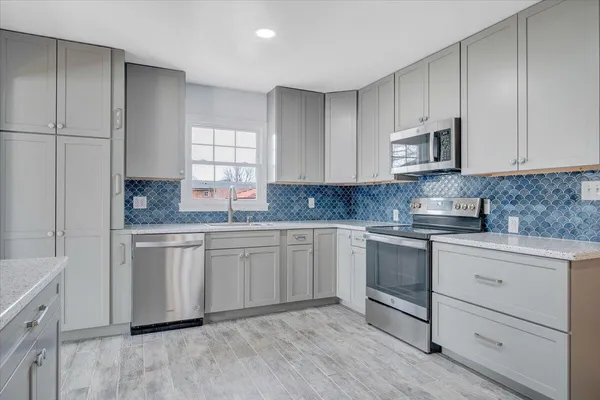 a kitchen with granite countertop cabinets stainless steel appliances a sink and a window