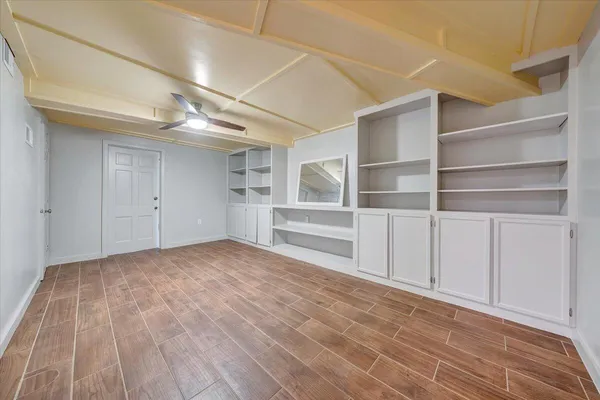 an empty room with windows and fan