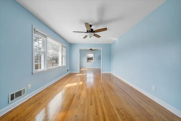 a view of empty room with wooden floor and fan