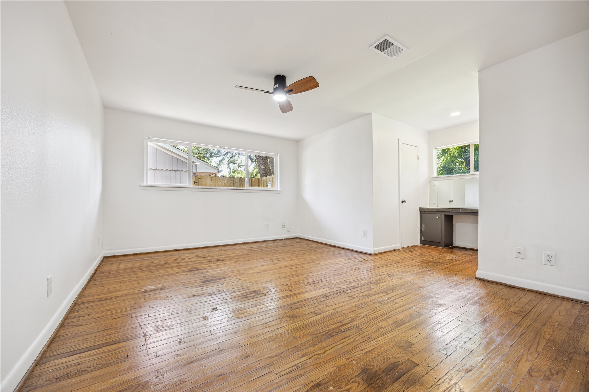 5419 Beechnut Street Houston, TX 77096 - Photo 17 of 28 Spacious primary bedroom with wood flooring, ceiling fan with light, built in desk area and large windows for natural light.