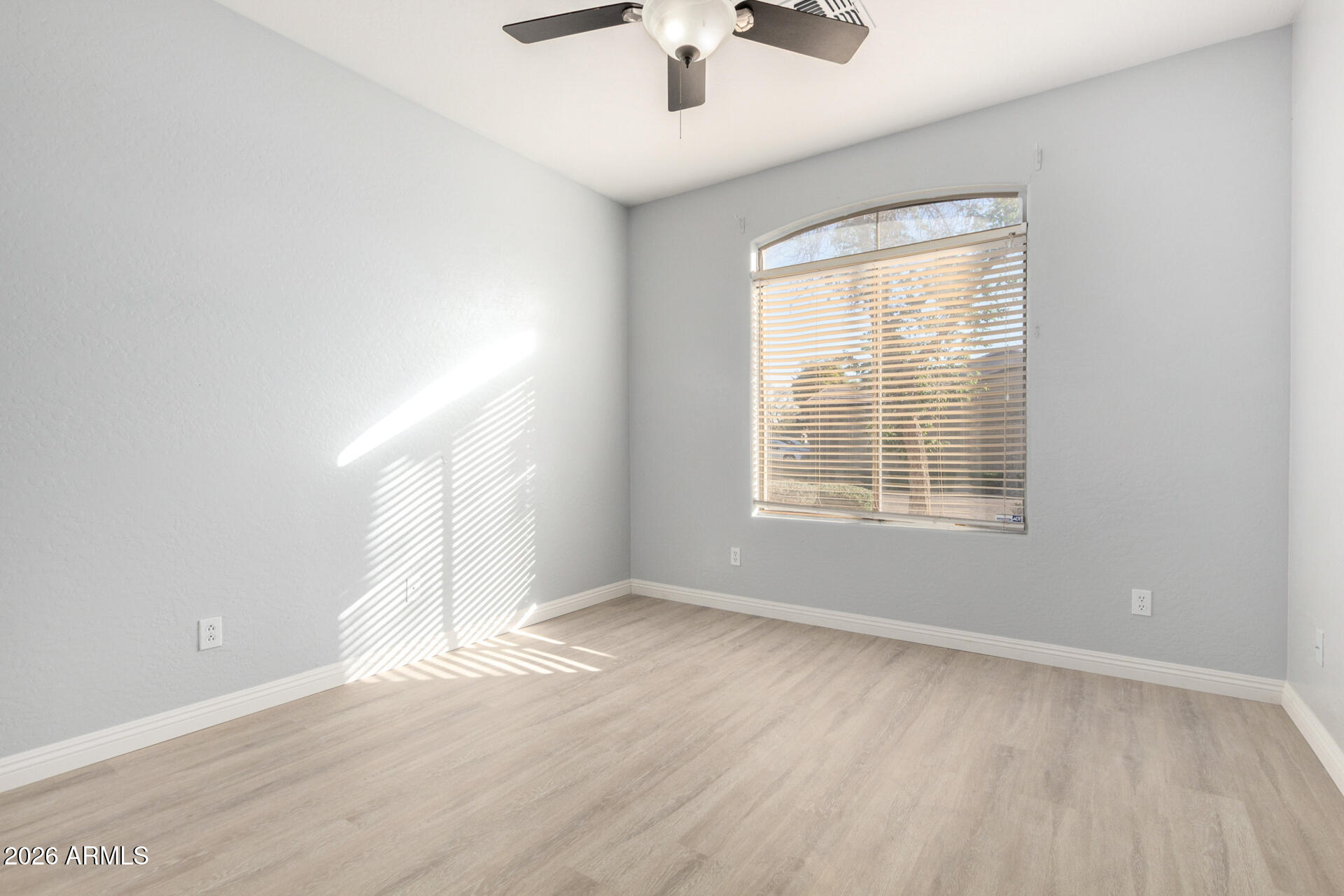 3230 South 74th Lane Phoenix, AZ 85043 - Photo 24 of 57 an empty room with wooden floor chandelier fan and windows
