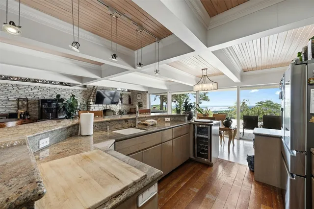 a kitchen with stainless steel appliances kitchen island granite countertop a dining table chairs and white cabinets