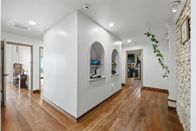 a view of a hallway with wooden floor and black appliances