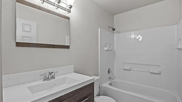 a bathroom with a bathtub shower sink and mirror