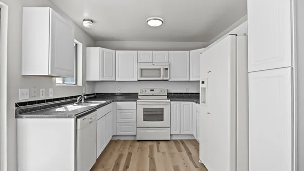 a kitchen with stainless steel appliances granite countertop a stove a sink and white cabinets