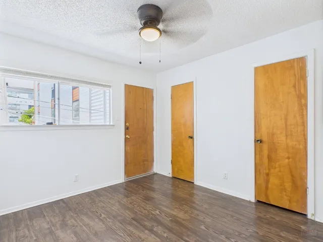 a view of an empty room with window and wooden floor