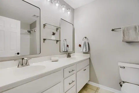 a bathroom with a double vanity sink mirror and toilet