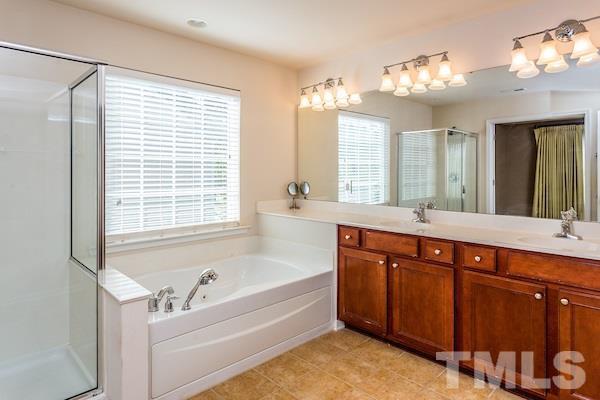 317 Euphoria Circle Cary, NC 27519 - Photo 21 of 22 a spacious bathroom with a tub a double vanity sink a large mirror and a bathtub next to a window