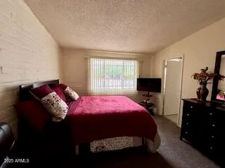 a bedroom with bed and a flat tv screen on dresser