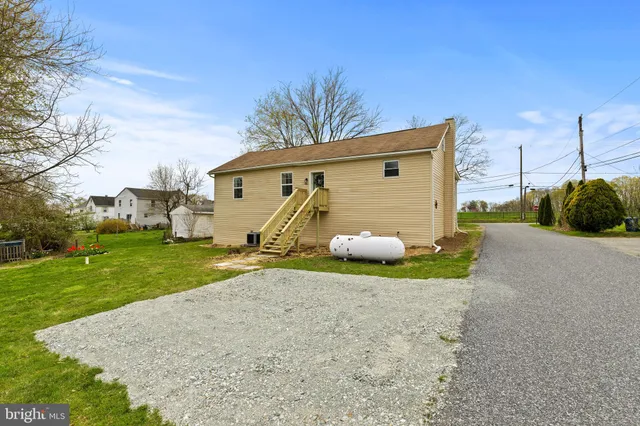 a view of a white house that has a big tree