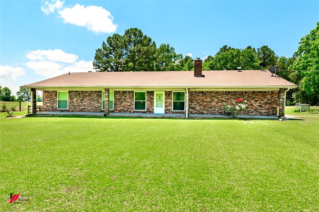 Ranch-style house featuring a chimney, a front lawn, brick siding, and roof with shingles