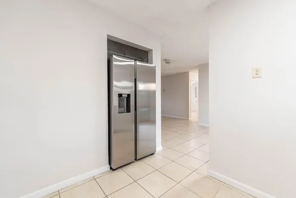 a view of a refrigerator in kitchen and an empty room