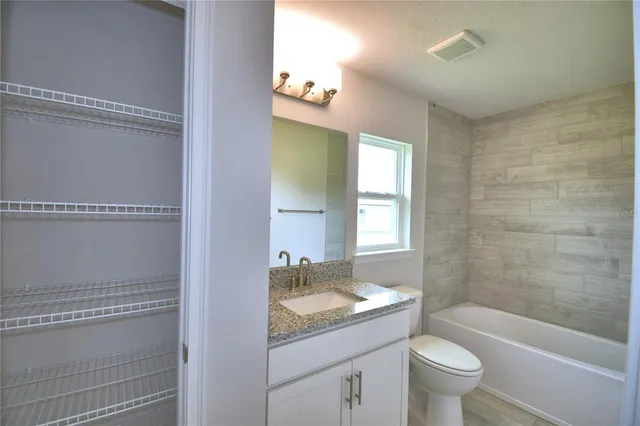 a bathroom with a granite countertop sink toilet a large mirror and a window