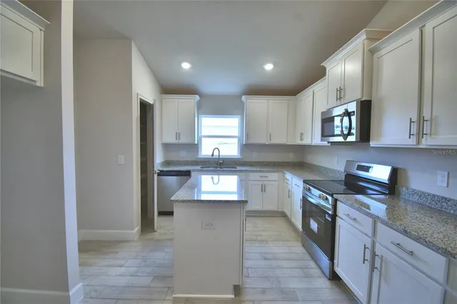 a kitchen with stainless steel appliances granite countertop a stove a sink and a refrigerator