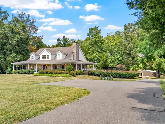 a front view of a house with a garden and trees