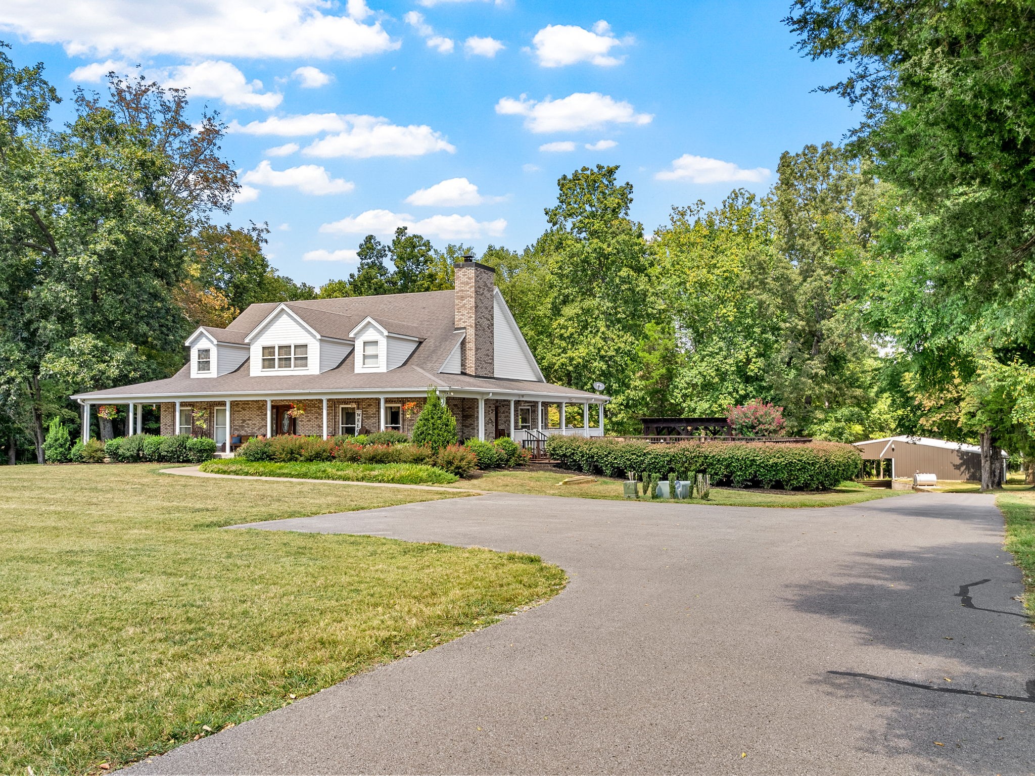 a front view of a house with a garden and trees