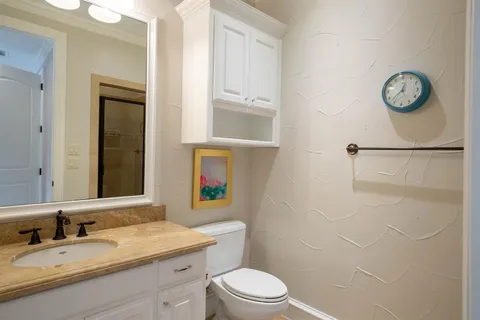a bathroom with a granite countertop toilet sink and mirror