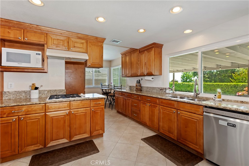 8527 Hillside Road Rancho Cucamonga, CA 91701 - Photo 14 of 50 a kitchen with stainless steel appliances granite countertop wooden cabinets a sink and a large window