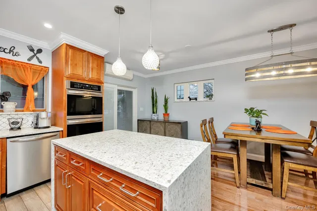 a kitchen with stainless steel appliances granite countertop a stove top oven a sink a dining table and chairs with wooden floor