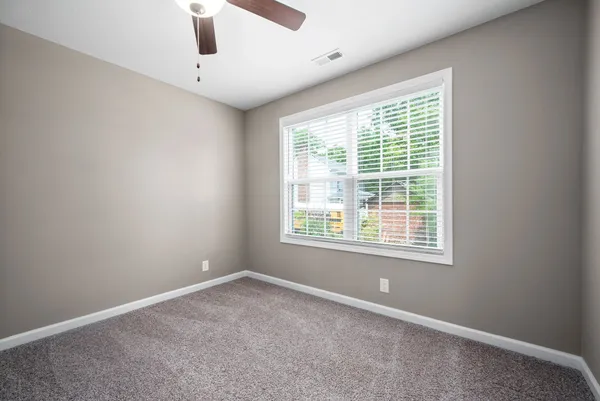 an empty room with a window and a ceiling fan
