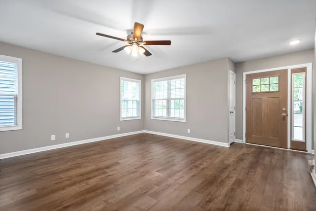 a view of an empty room with window and wooden floor