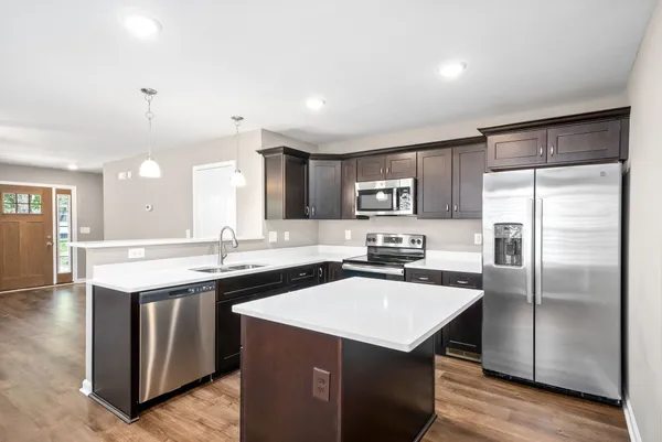 a kitchen with a sink a center island stainless steel appliances and cabinets