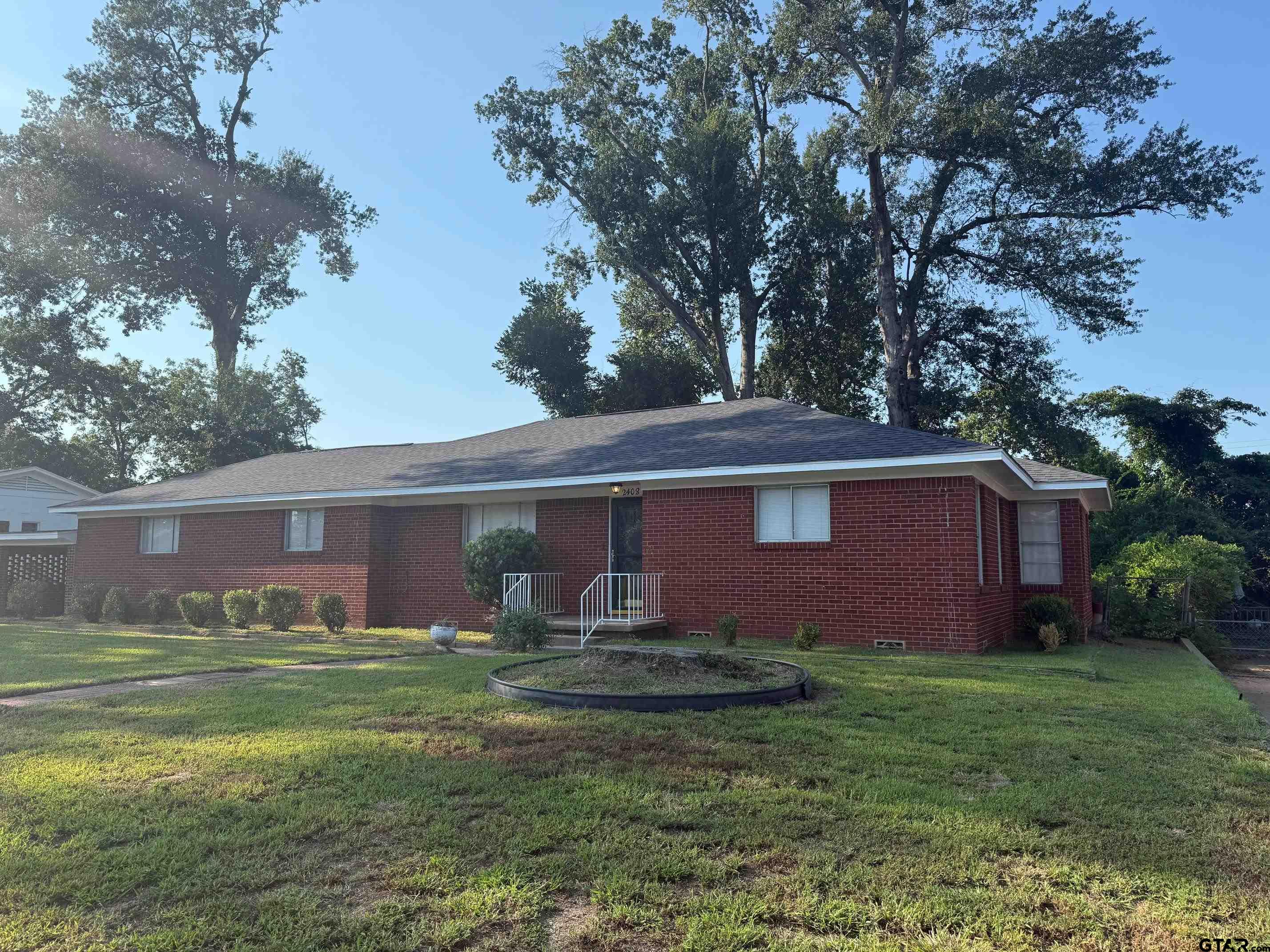 2408 Hunter Street Tyler, TX 75701 - Photo 2 of 33 a backyard of a house with table and chairs plants and large tree