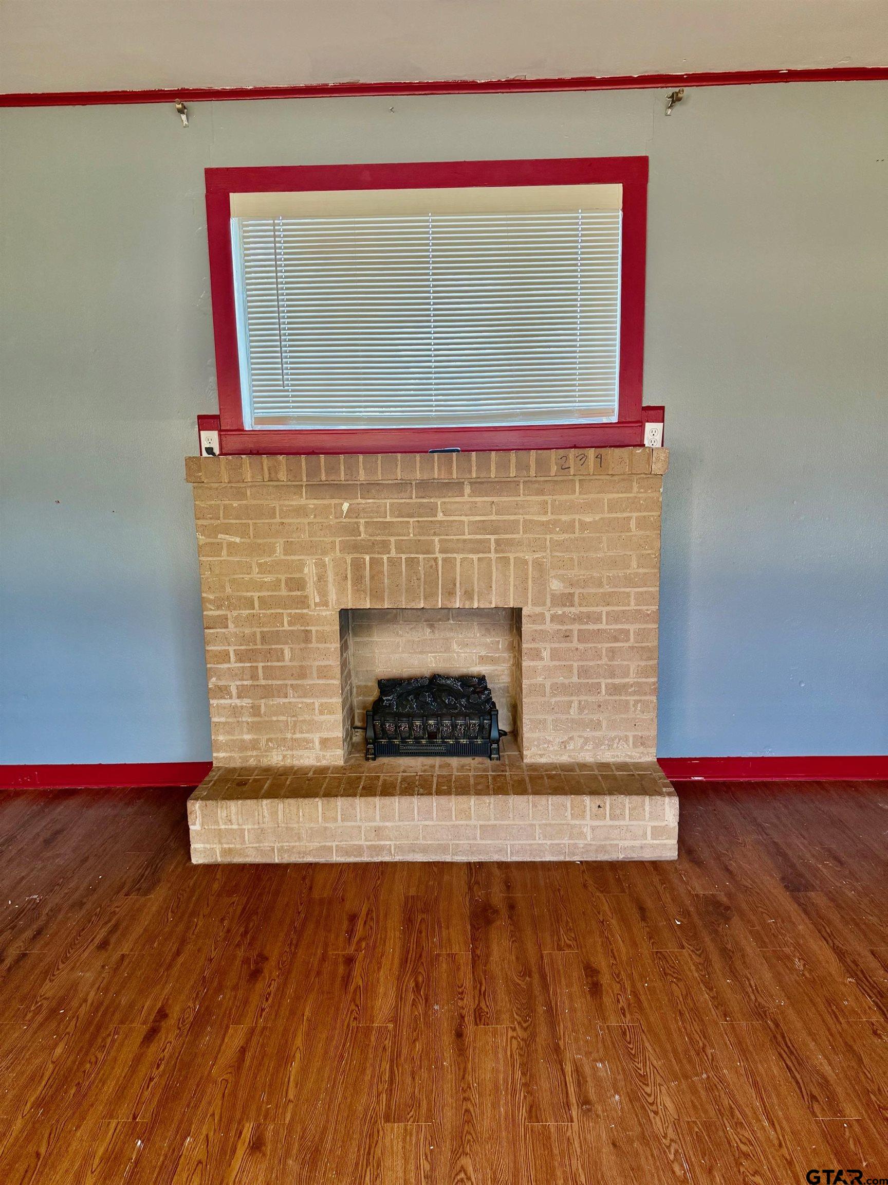 2408 Hunter Street Tyler, TX 75701 - Photo 28 of 33 a living room with a fireplace and a wooden floor