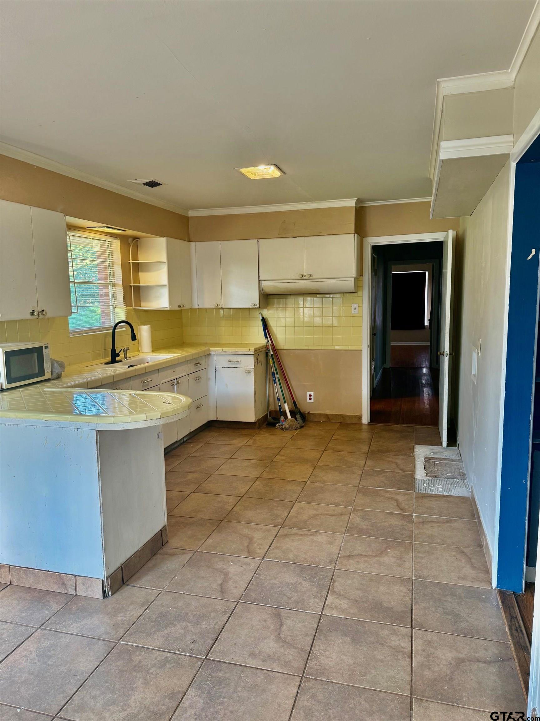 2408 Hunter Street Tyler, TX 75701 - Photo 10 of 33 a room with kitchen island a sink a counter and a stove top oven