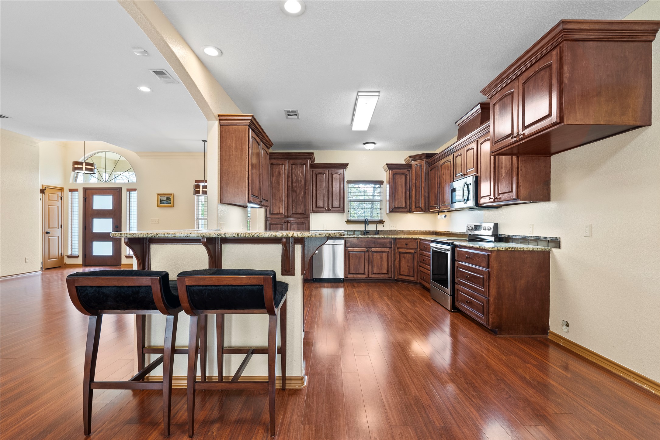 330 Arbors Circle Elgin, TX 78621 - Photo 8 of 37 Kitchen with visible vents, a peninsula, stainless steel appliances, dark wood-type flooring, and a kitchen breakfast bar
