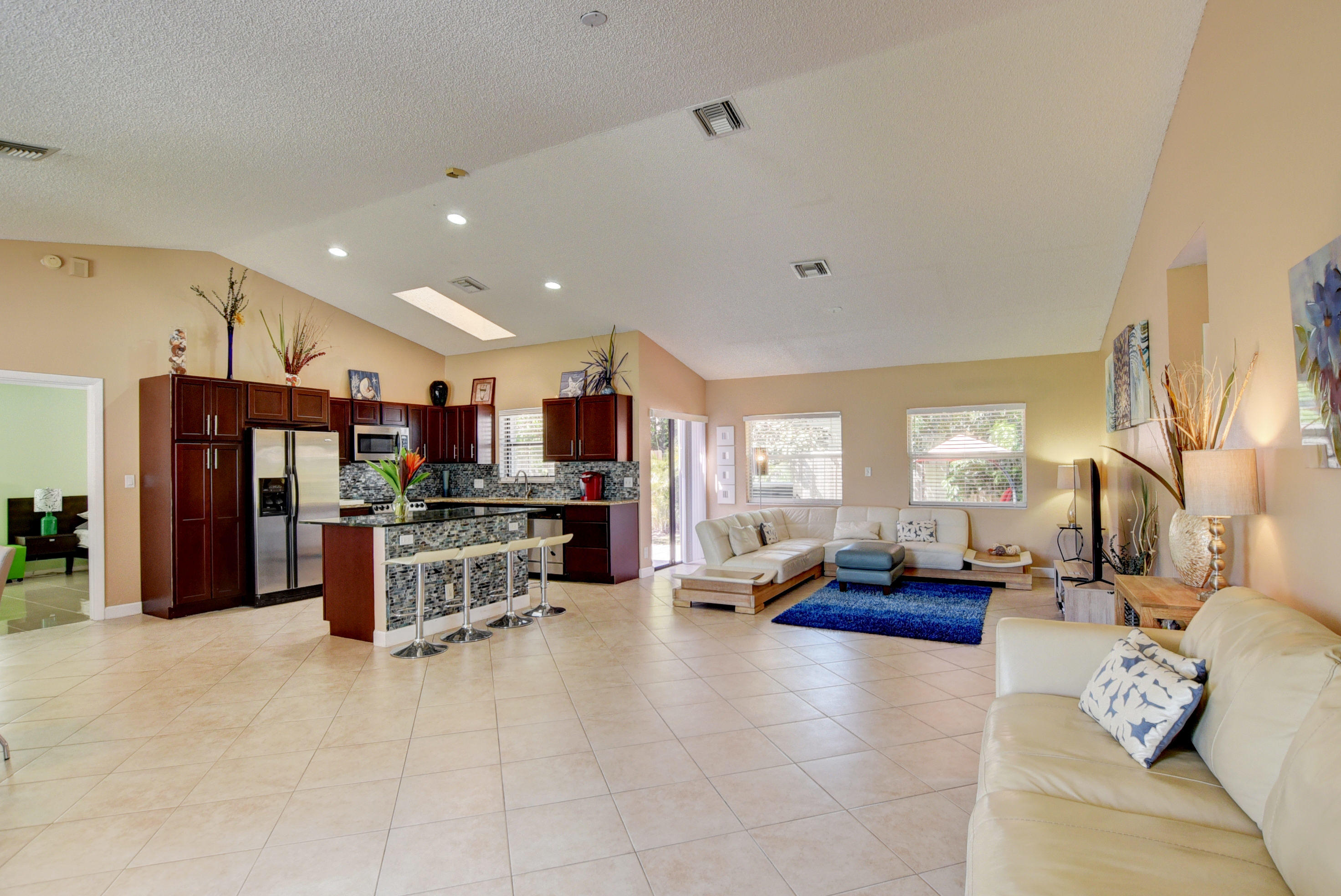 a living room with stainless steel appliances furniture a rug and a view of kitchen