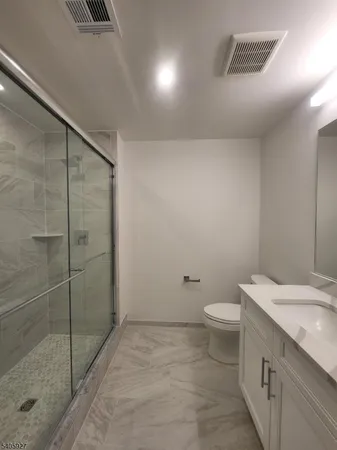 a bathroom with a granite countertop sink a toilet and shower