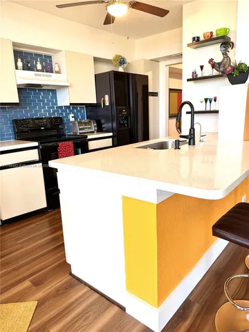 a kitchen with kitchen island a stove a refrigerator and a sink with wooden floor