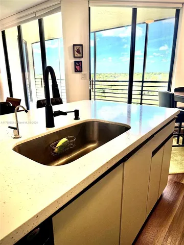 a view of a kitchen with kitchen island a large window a sink and counter top