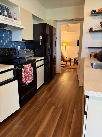 a kitchen with granite countertop a stove a refrigerator and wooden floor