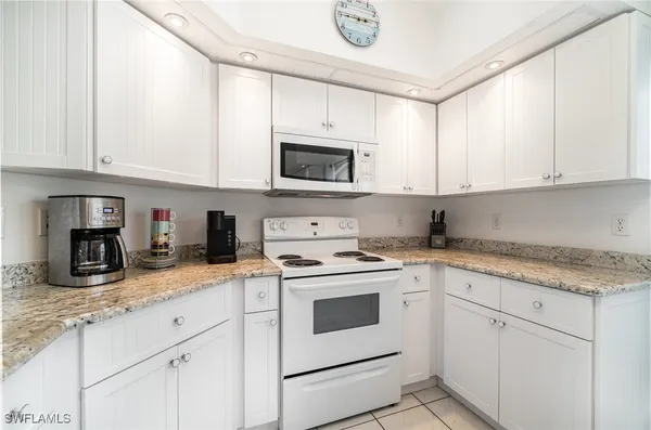 a kitchen with granite countertop white cabinets and white appliances