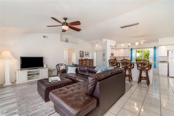 a living room with furniture a flat screen tv and kitchen view