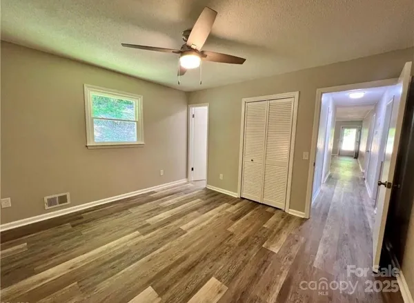 an empty room with wooden floor and a ceiling fan