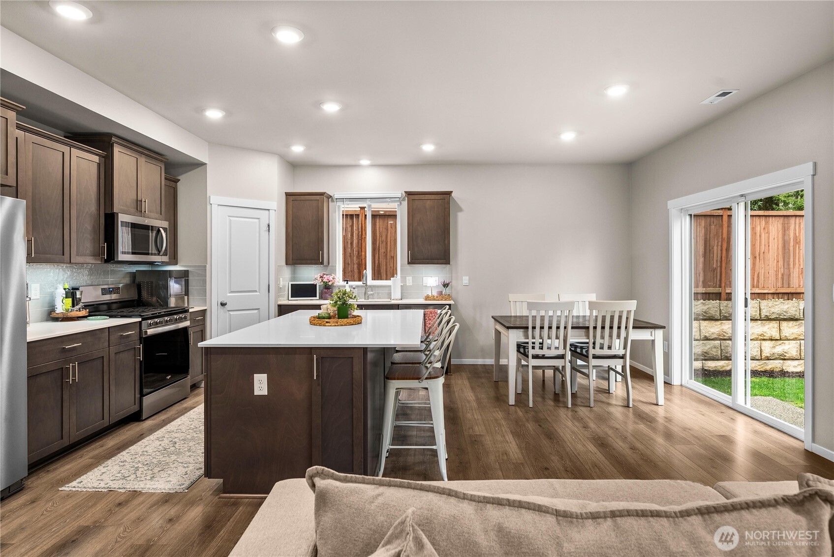 1081 Southwest Pendleton Way Port Orchard, WA 98367 - Photo 5 of 40 a kitchen with kitchen island granite countertop a stove top oven a sink a dining table and chairs with wooden floor