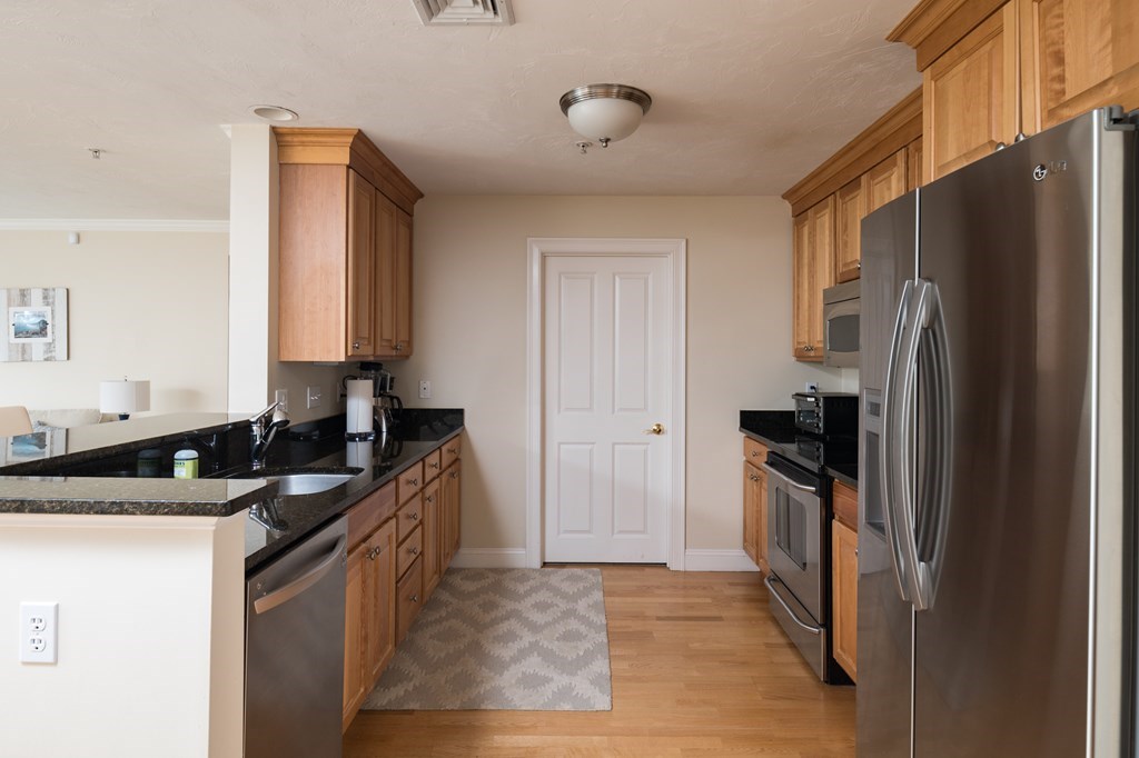 29 Maple Street, Unit E Canton, MA 02021 - Photo 7 of 23 a kitchen with granite countertop a refrigerator and a sink