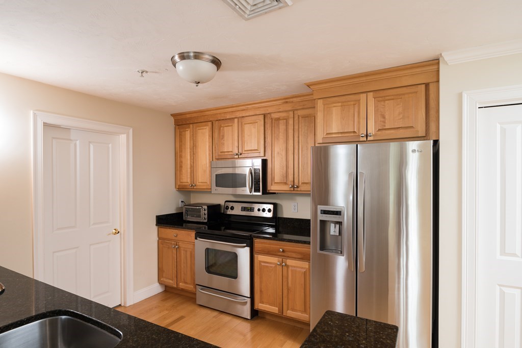 29 Maple Street, Unit E Canton, MA 02021 - Photo 9 of 23 a kitchen with stainless steel appliances a refrigerator stove and sink
