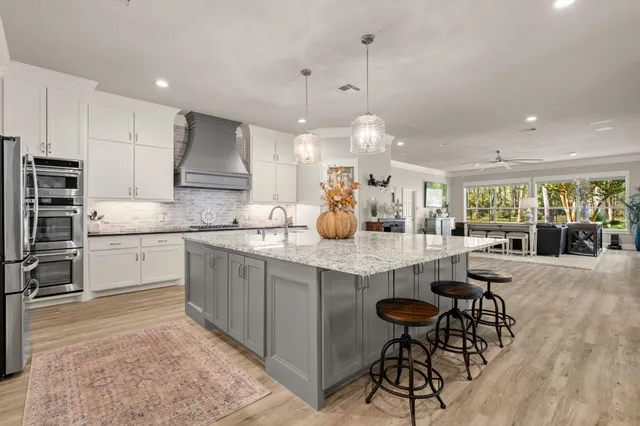 a kitchen with stainless steel appliances kitchen island granite countertop a table chairs sink and cabinets
