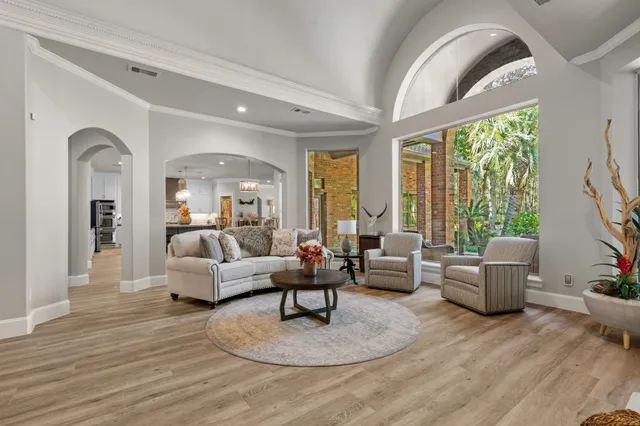 a room with stainless steel appliances kitchen island granite countertop a table chairs and a wooden floor