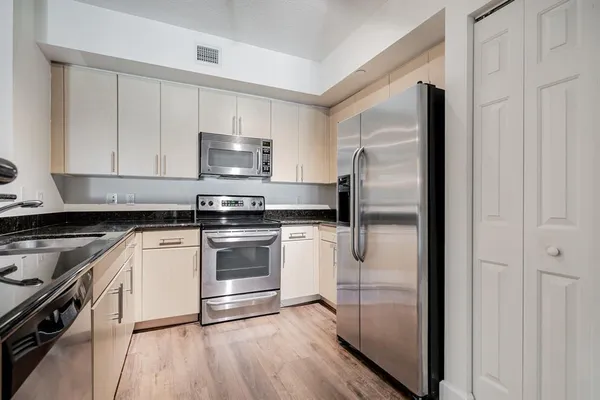 a kitchen with a refrigerator stove and white cabinets
