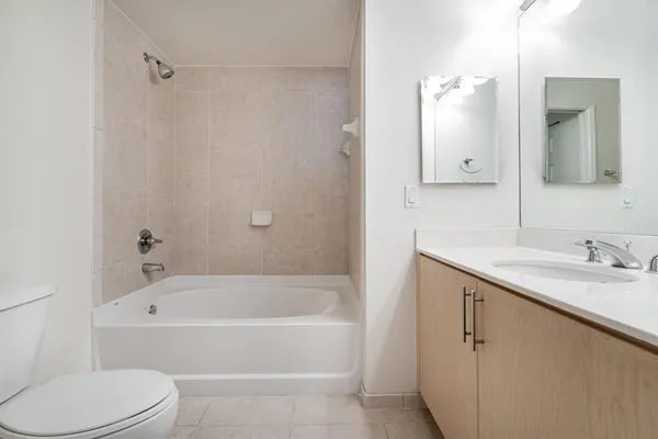 a bathroom with a granite countertop bathtub shower sink vanity and toilet