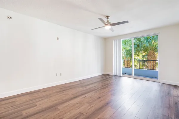 an empty room with wooden floor fan and windows