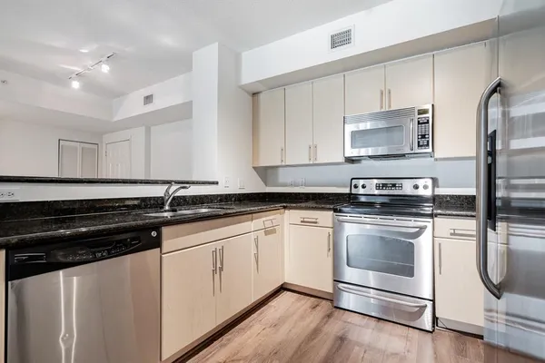 a kitchen with granite countertop white cabinets stainless steel appliances and a sink