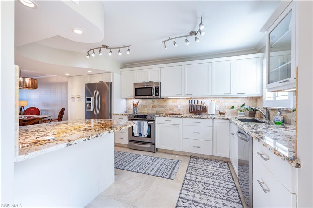 800 River Point Drive, Unit 207 Naples, FL 34102 - Photo 15 of 47 a kitchen with kitchen island granite countertop a sink appliances cabinets and counter space