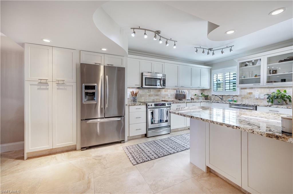 800 River Point Drive, Unit 207 Naples, FL 34102 - Photo 17 of 47 a kitchen with granite countertop a refrigerator oven a sink dishwasher and white cabinets with wooden floor